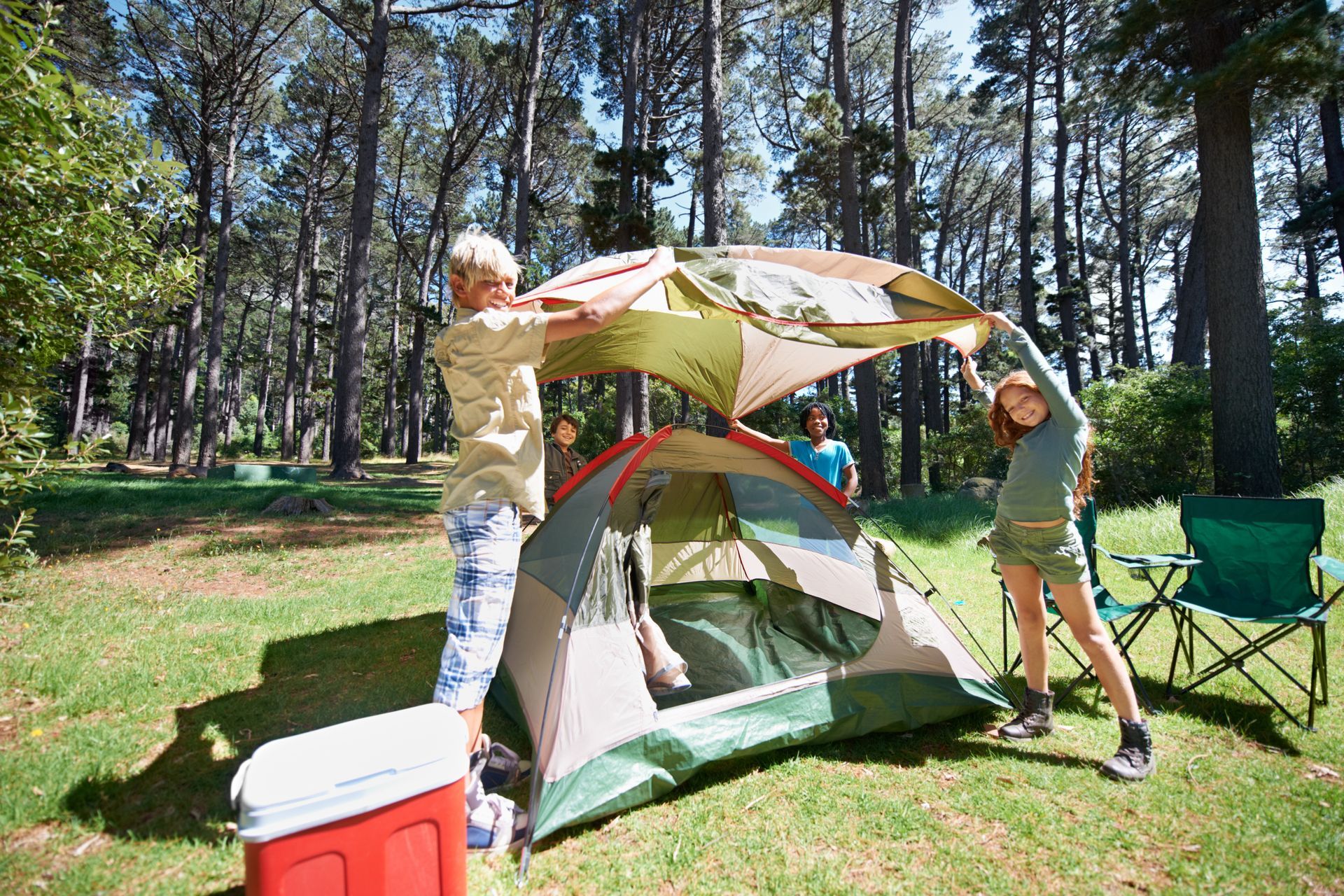 A man and a woman are setting up a tent in the woods.