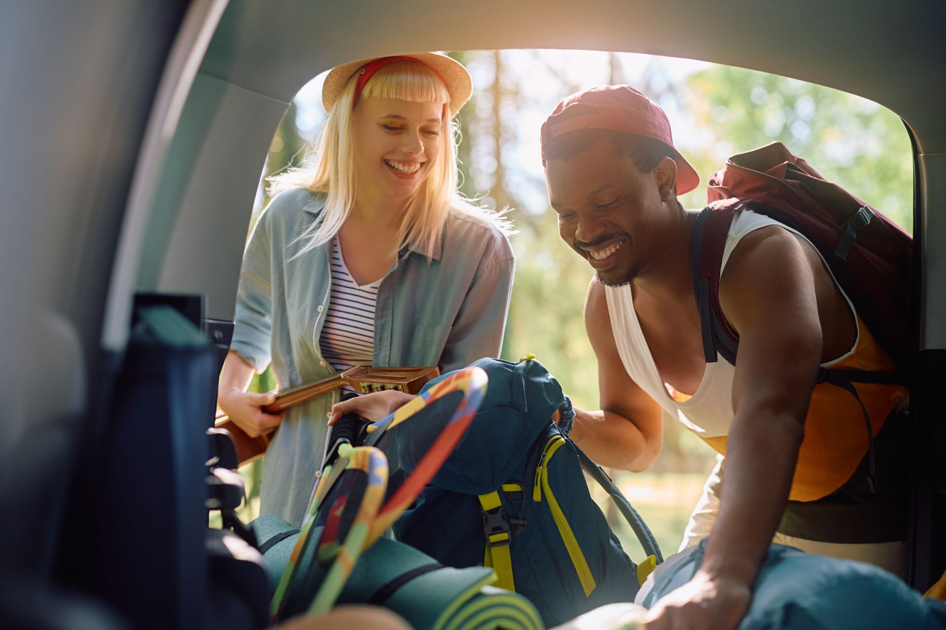 A man and a woman are looking in the back of a car.