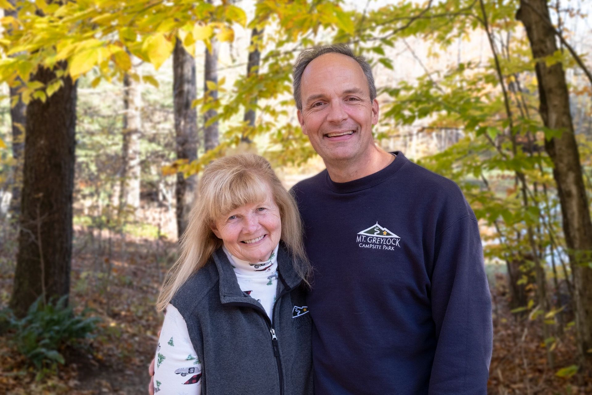 a man and a woman are posing for a picture in the woods .