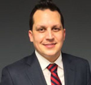 A man in a suit and tie is smiling for the camera.