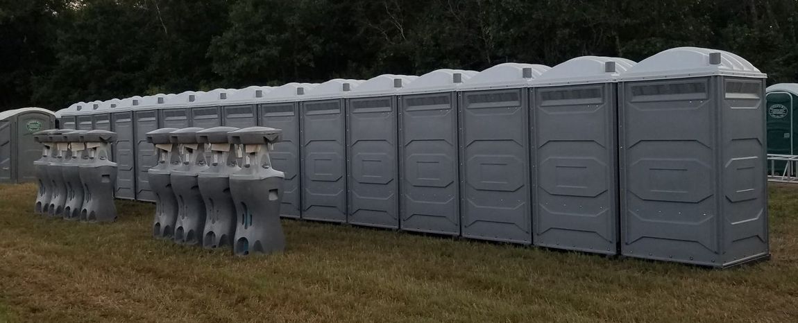 A row of portable toilets are lined up in a field