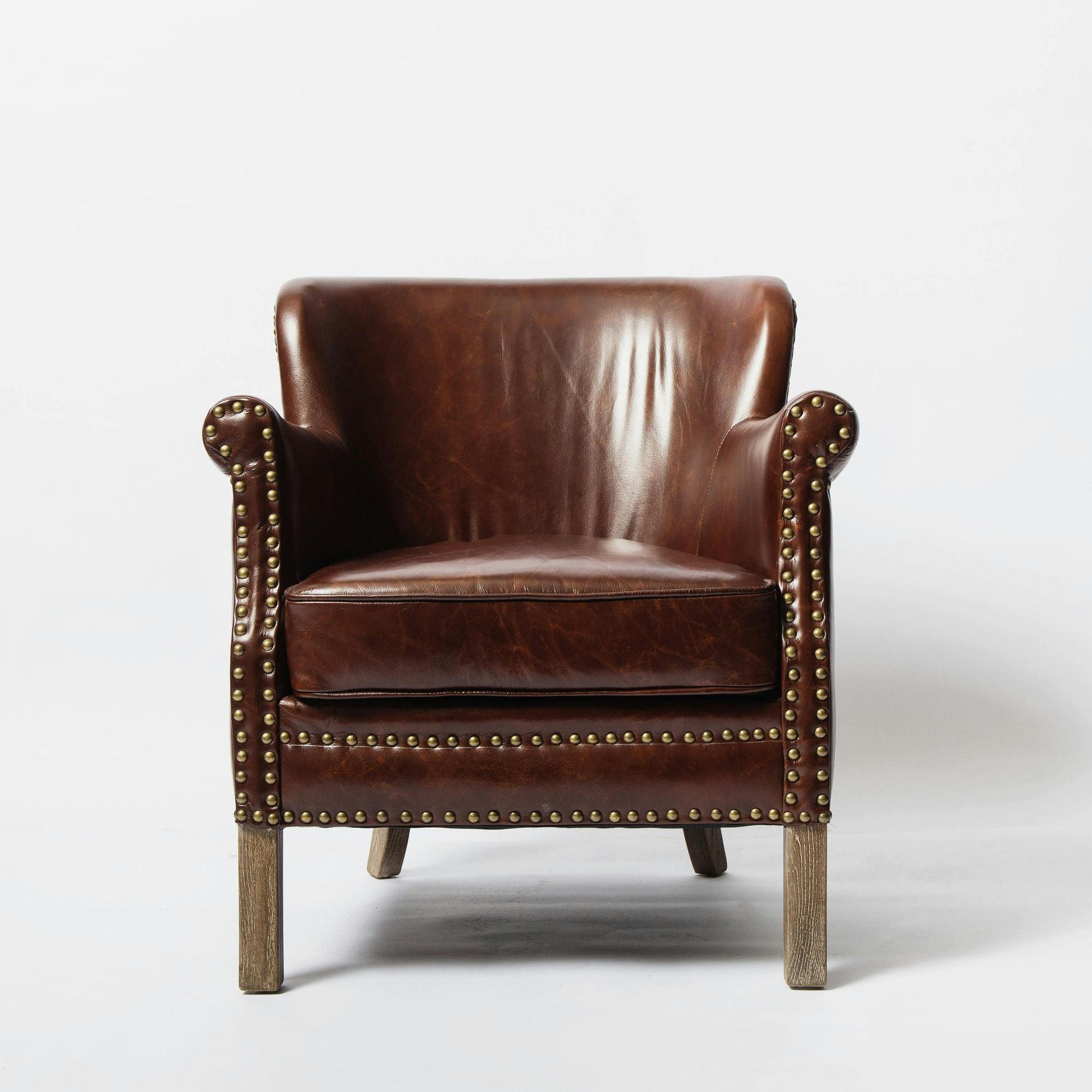A brown leather chair with studs on the arm rests
