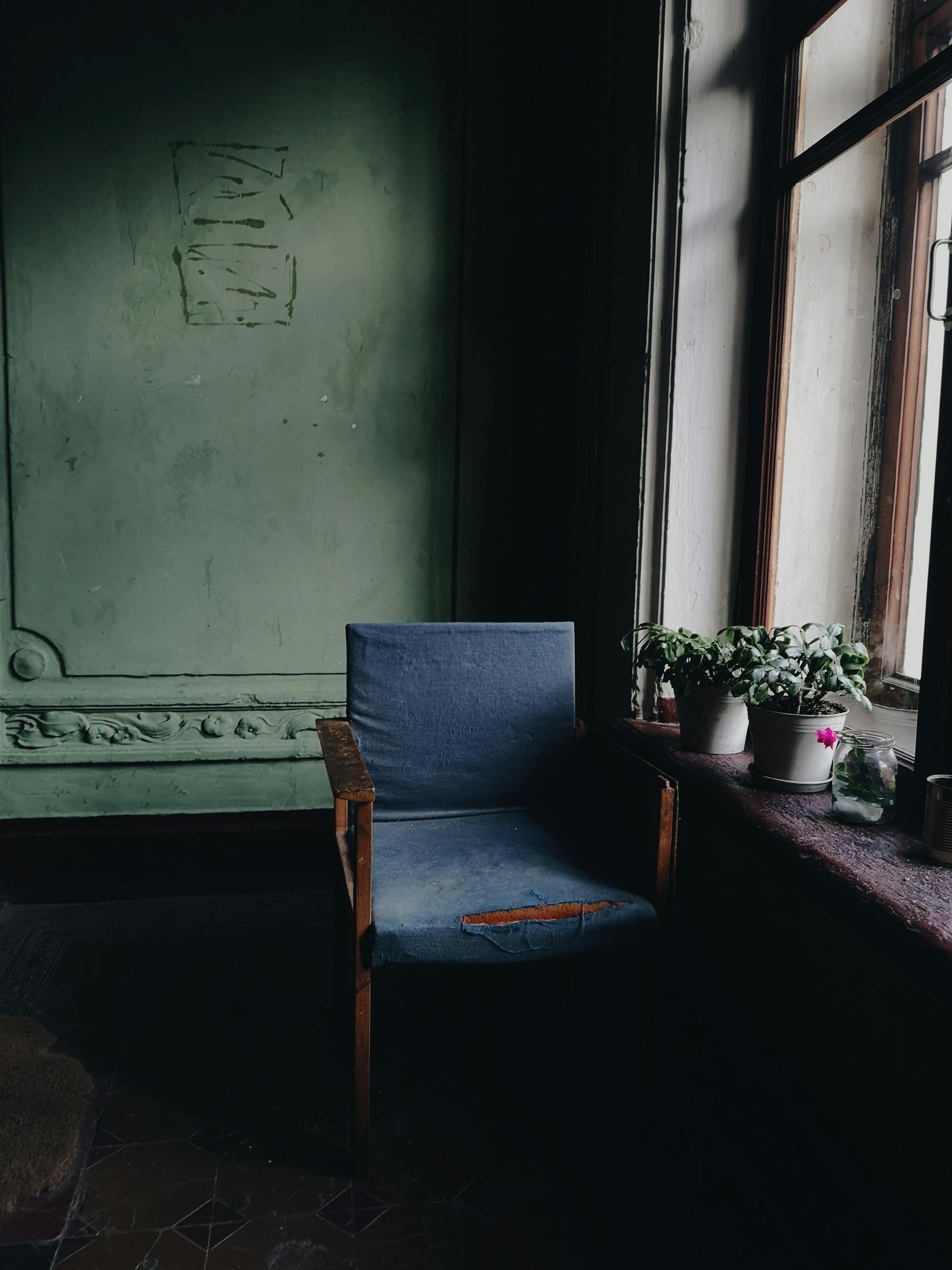 A chair is sitting in front of a window in a dark room.