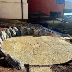 Stone fire pit on a cracked, light-colored surface, surrounded by large rocks and landscape.
