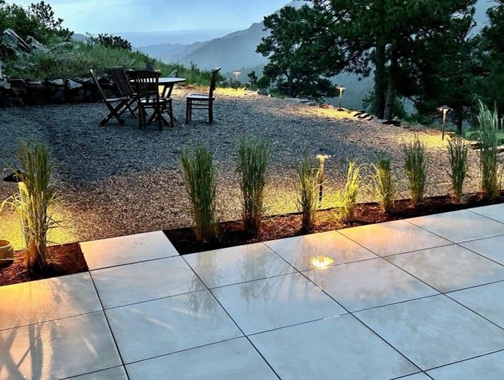 Patio with illuminated landscaping, gravel seating area, table, chairs, and mountain view.