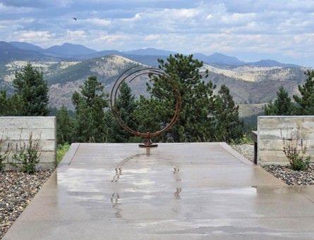Sculpture of linked rings on a concrete patio overlooking a mountain range.