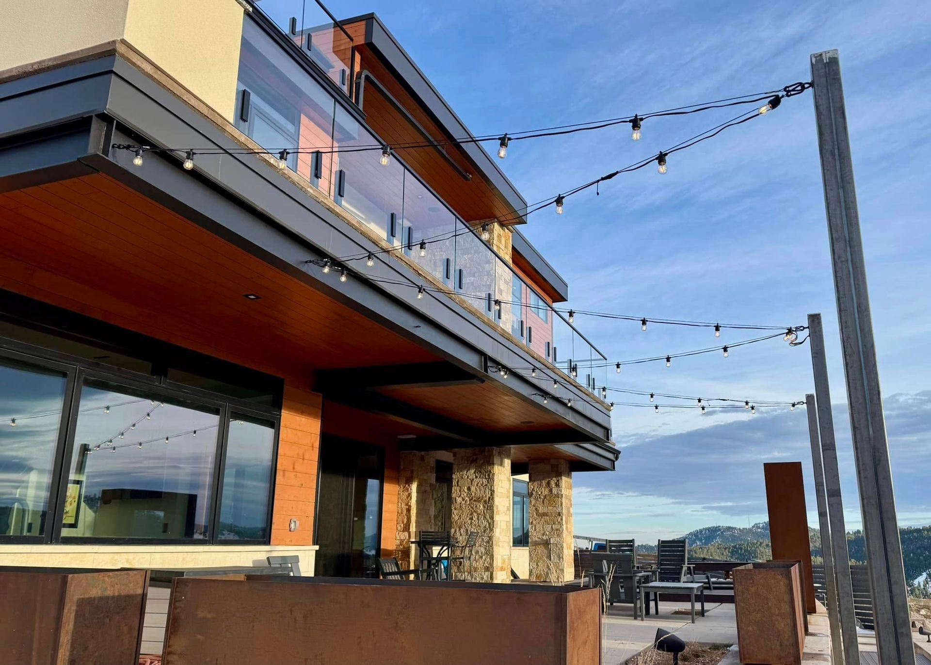 Modern building exterior with string lights, balcony, and stone accents.