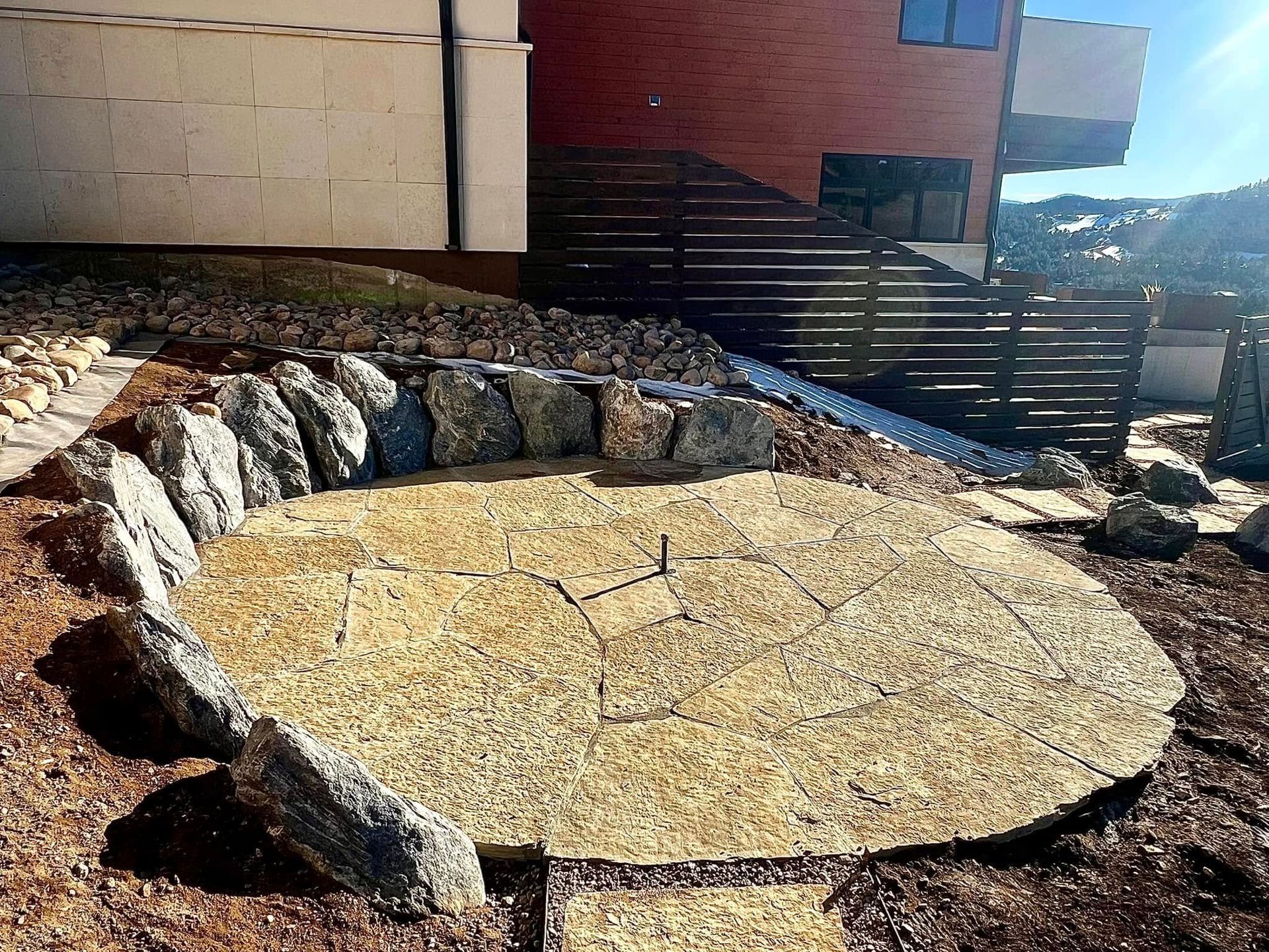 Stone fire pit on a cracked, light-colored surface, surrounded by large rocks and landscape.