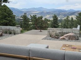 Patio with mountain view, concrete, stone walls, trees, cloudy sky.