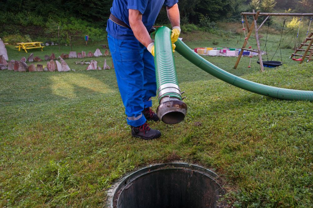 Worker Lowering a Hose Into a Large Open Manhole on A Grassy Lawn — Tamworth Septic & Liquid Waste in Wallabadah, NSW