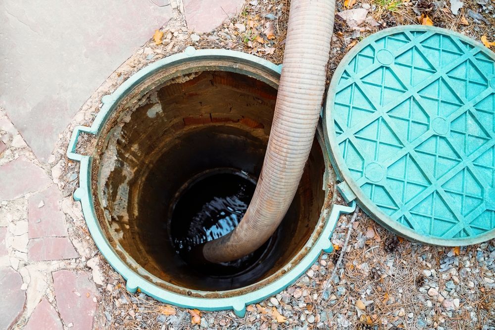 Open Manhole with A Hose Inserted Turquoise Cover Lies Beside It — Tamworth Septic & Liquid Waste in Wallabadah, NSW