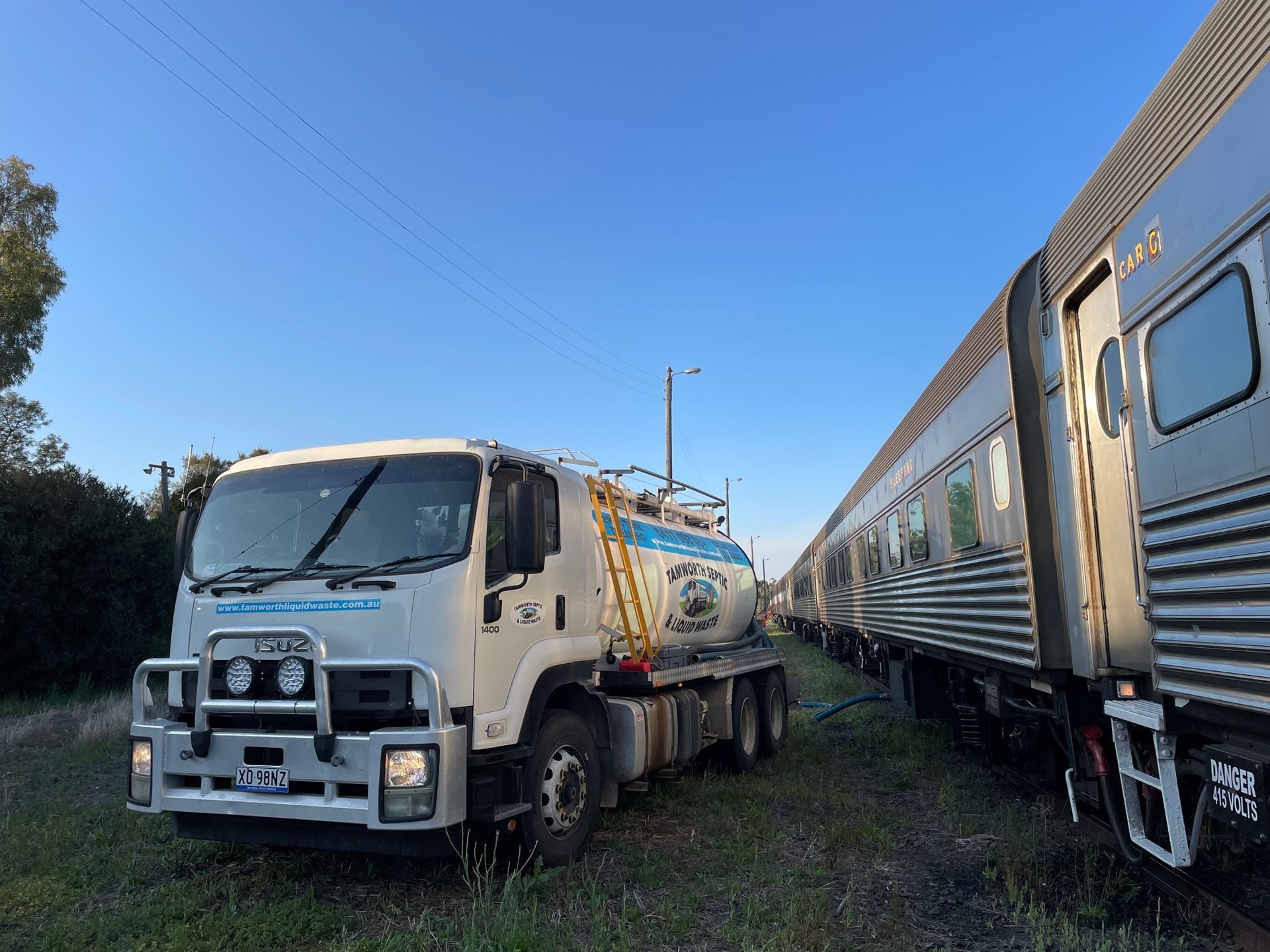 White Tanker Truck Beside a Silver Passenger Train on Grass — Tamworth Septic & Liquid Waste in Quirindi, NSW