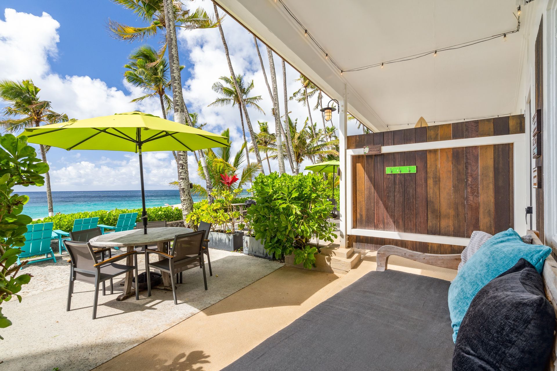 Modern studio apartment with ocean view, gray accent wall, bed, couch, and ceiling fan.