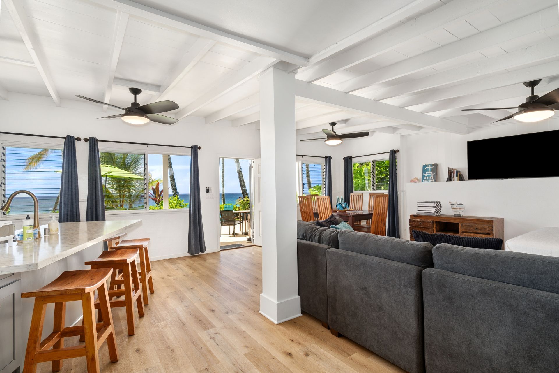Bright living room with wood floors, bar seating, and ocean view through windows.