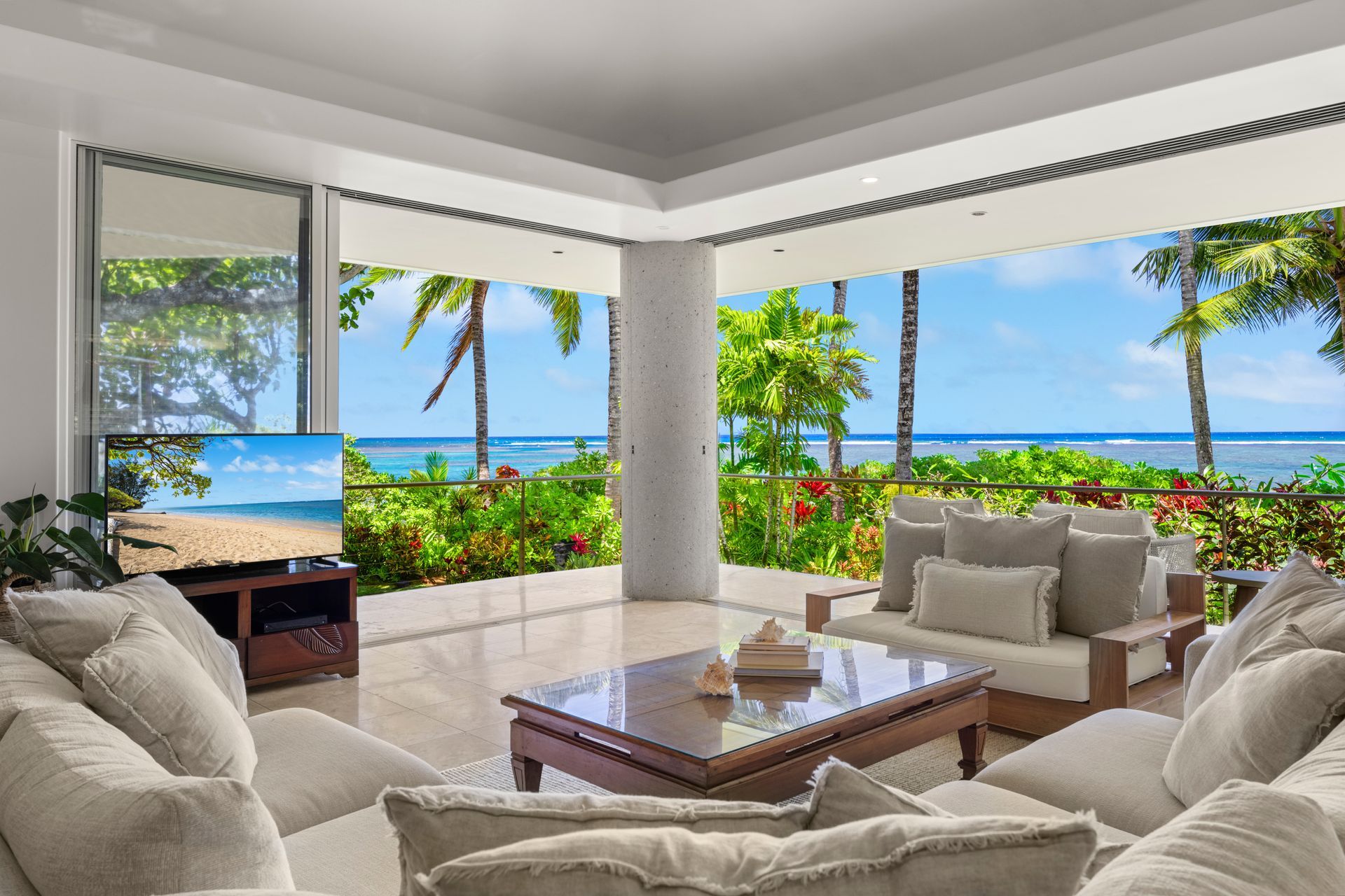 Living room with open ocean view; tan couches, TV, and coffee table.