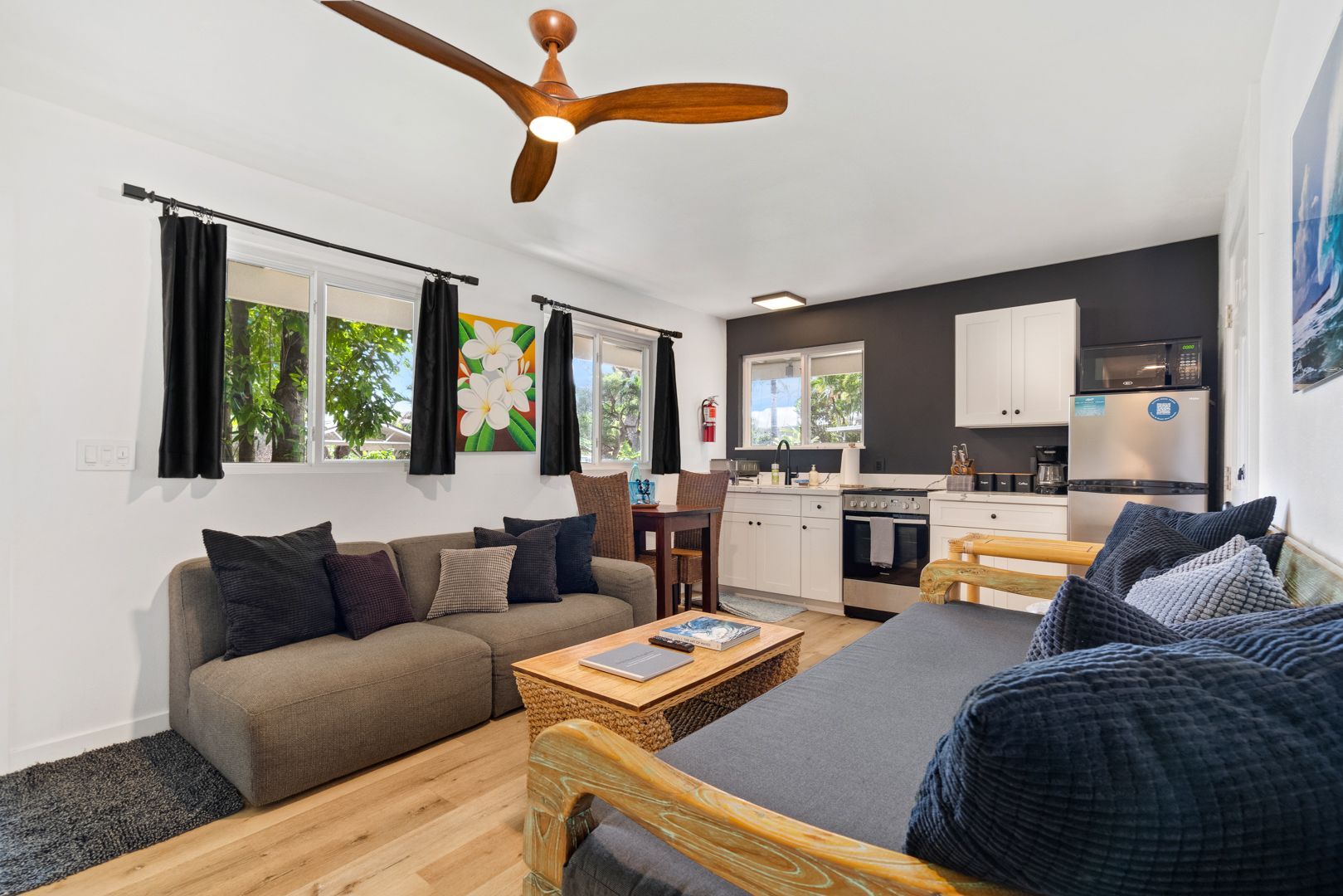 Cozy studio apartment with a living area, kitchenette, and a wooden ceiling fan.