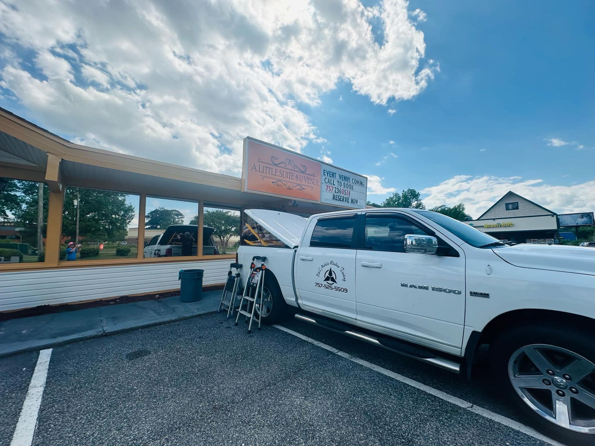 A white truck is parked in a parking lot in front of a restaurant.
