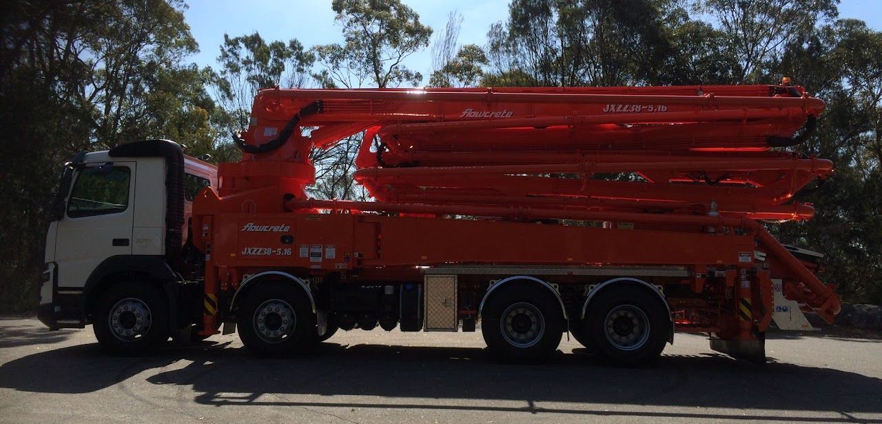 A red concrete pump truck is parked on the side of the road.