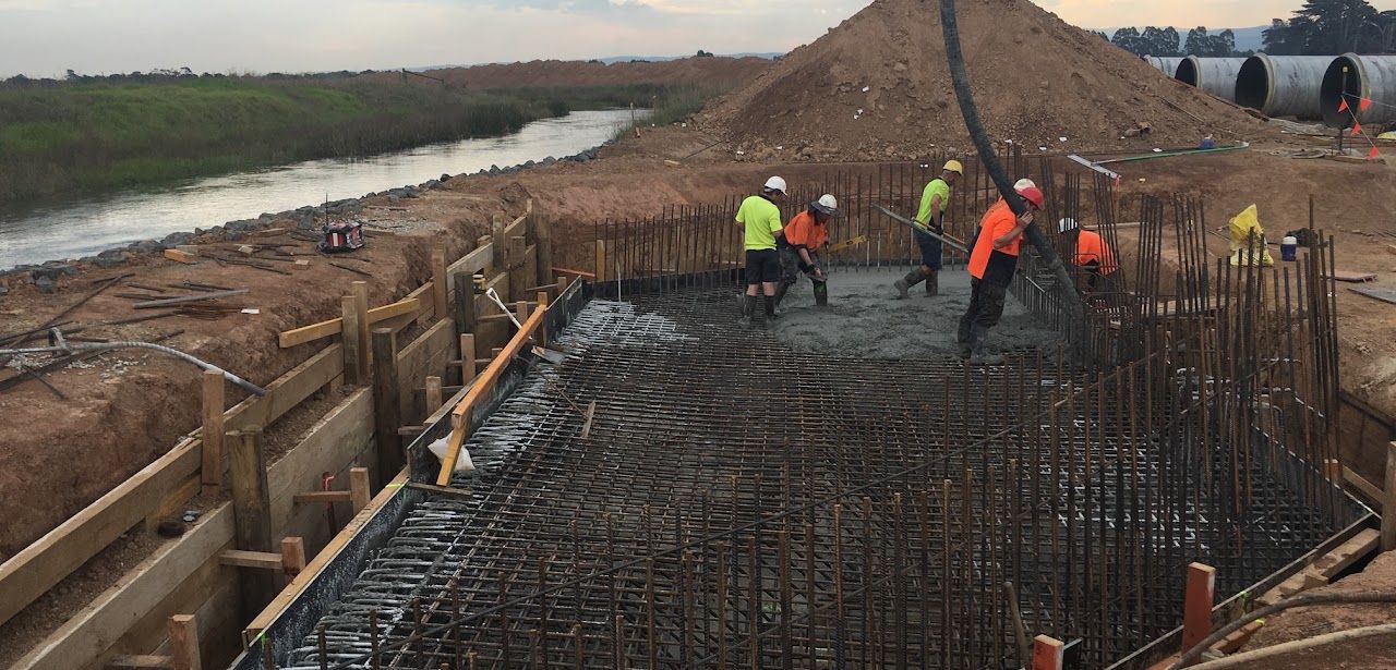 A group of construction workers are working on a construction site next to a river.