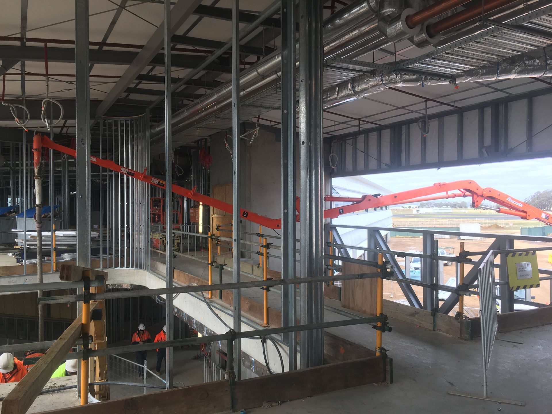 The inside of a building under construction with scaffolding and pipes.