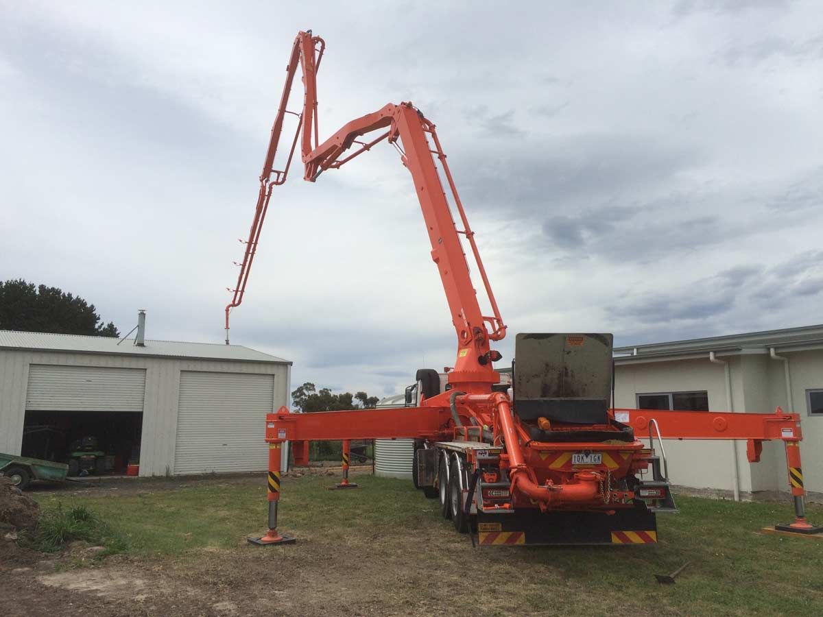 An orange truck with a concrete pump attached to it