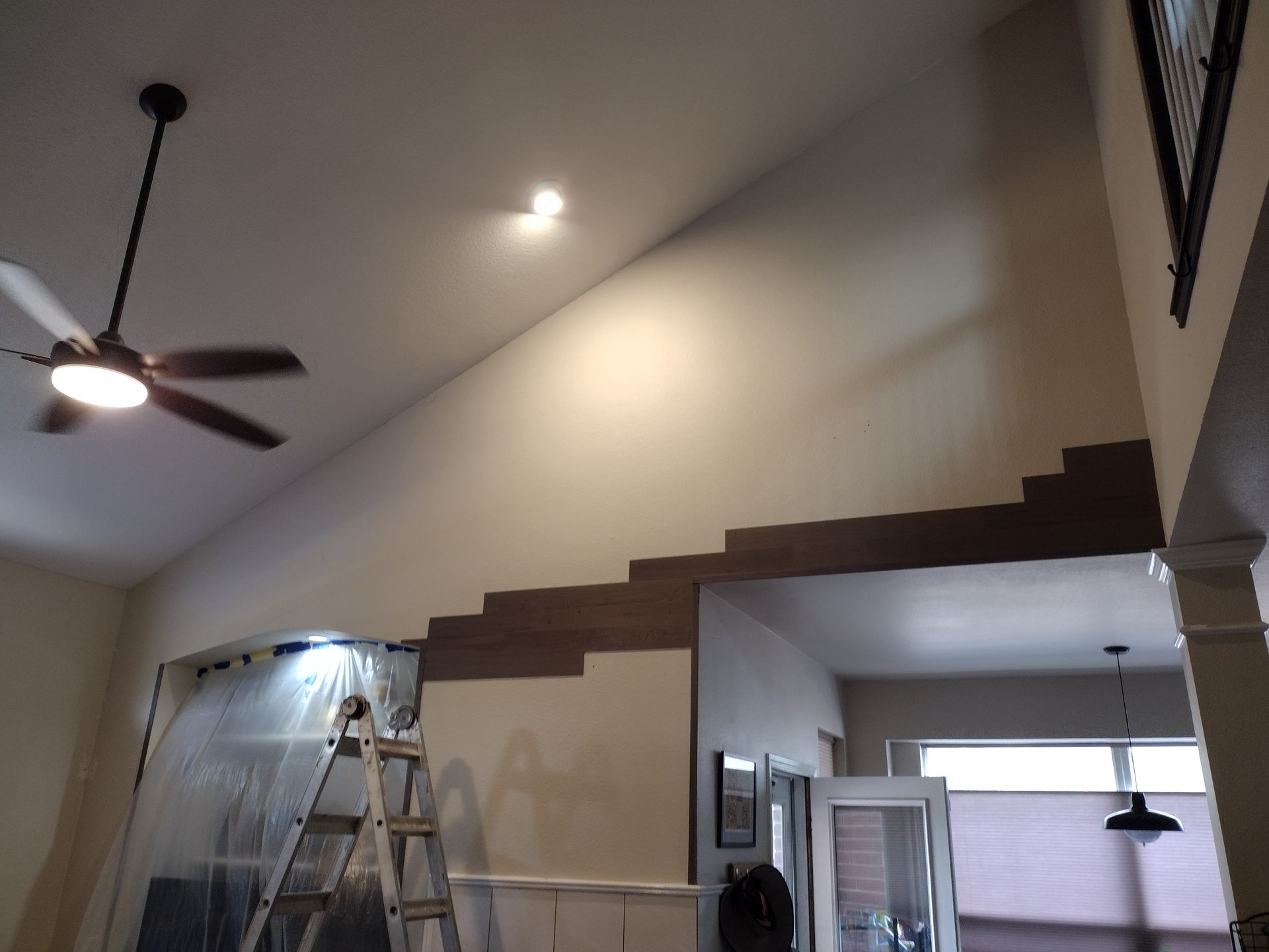 Ceiling light fixture hanging above a dark-framed window.  Light glows from the lamp. White walls.