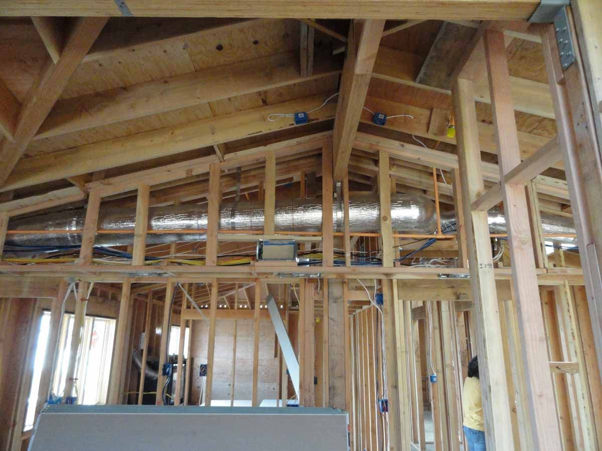 A man is standing in the middle of a wooden house under construction.