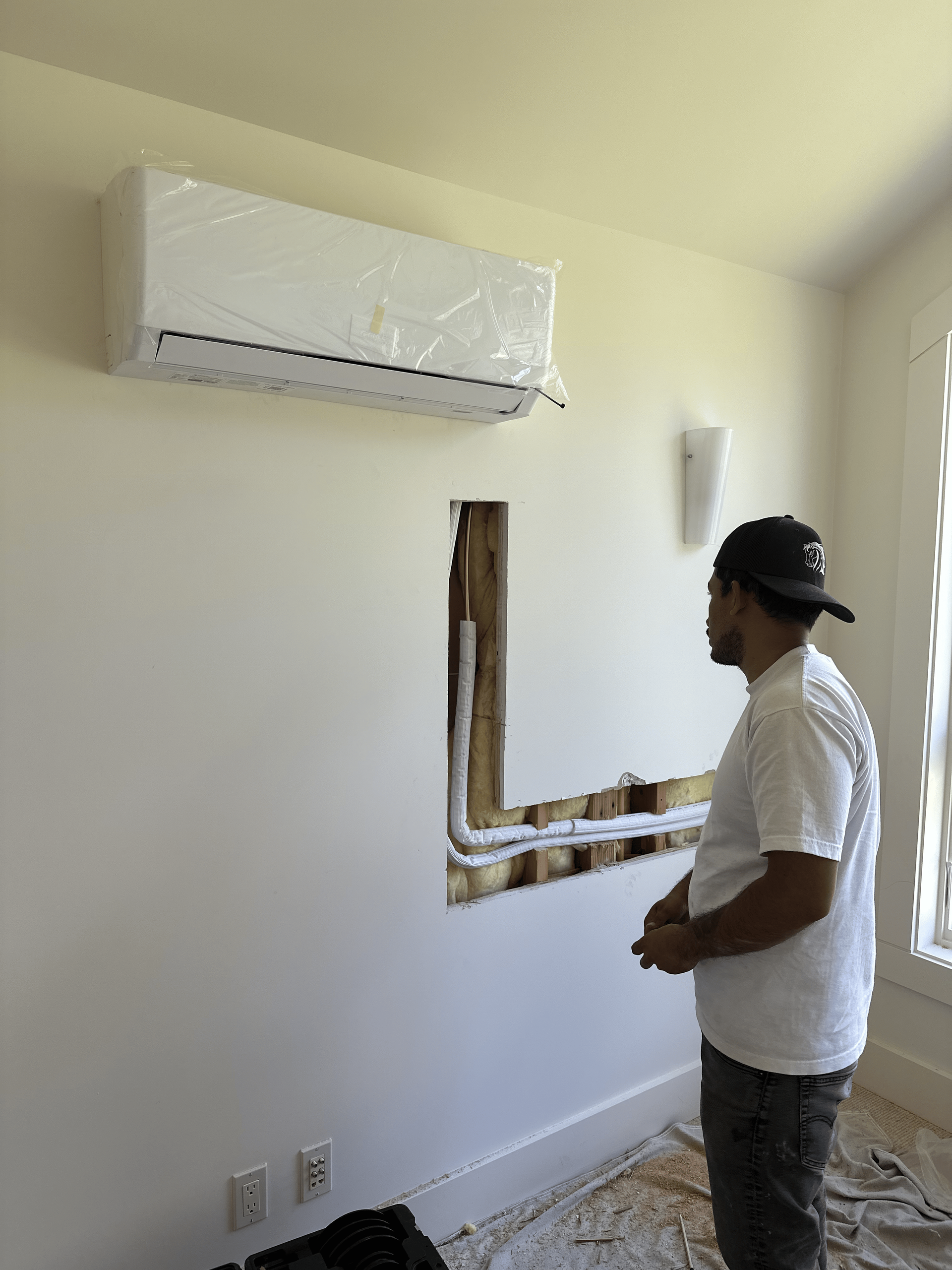 A man is installing an air conditioner in a room.
