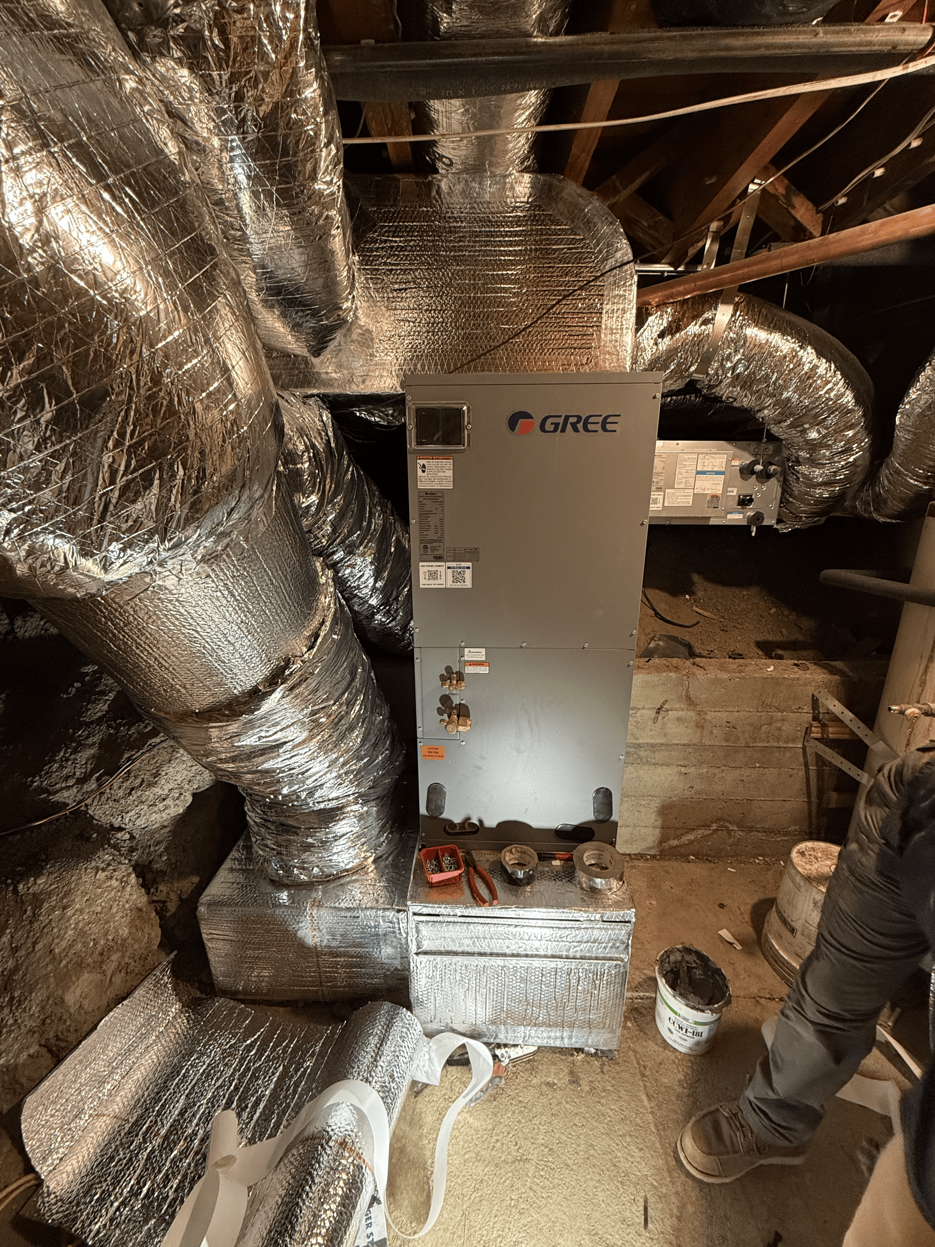 A man is working on an air conditioner in a basement.
