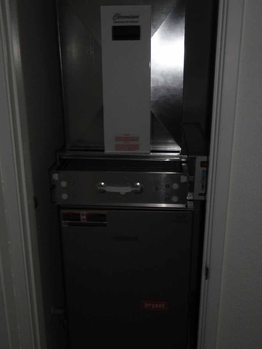 A stainless steel refrigerator is sitting in a closet next to a door.
