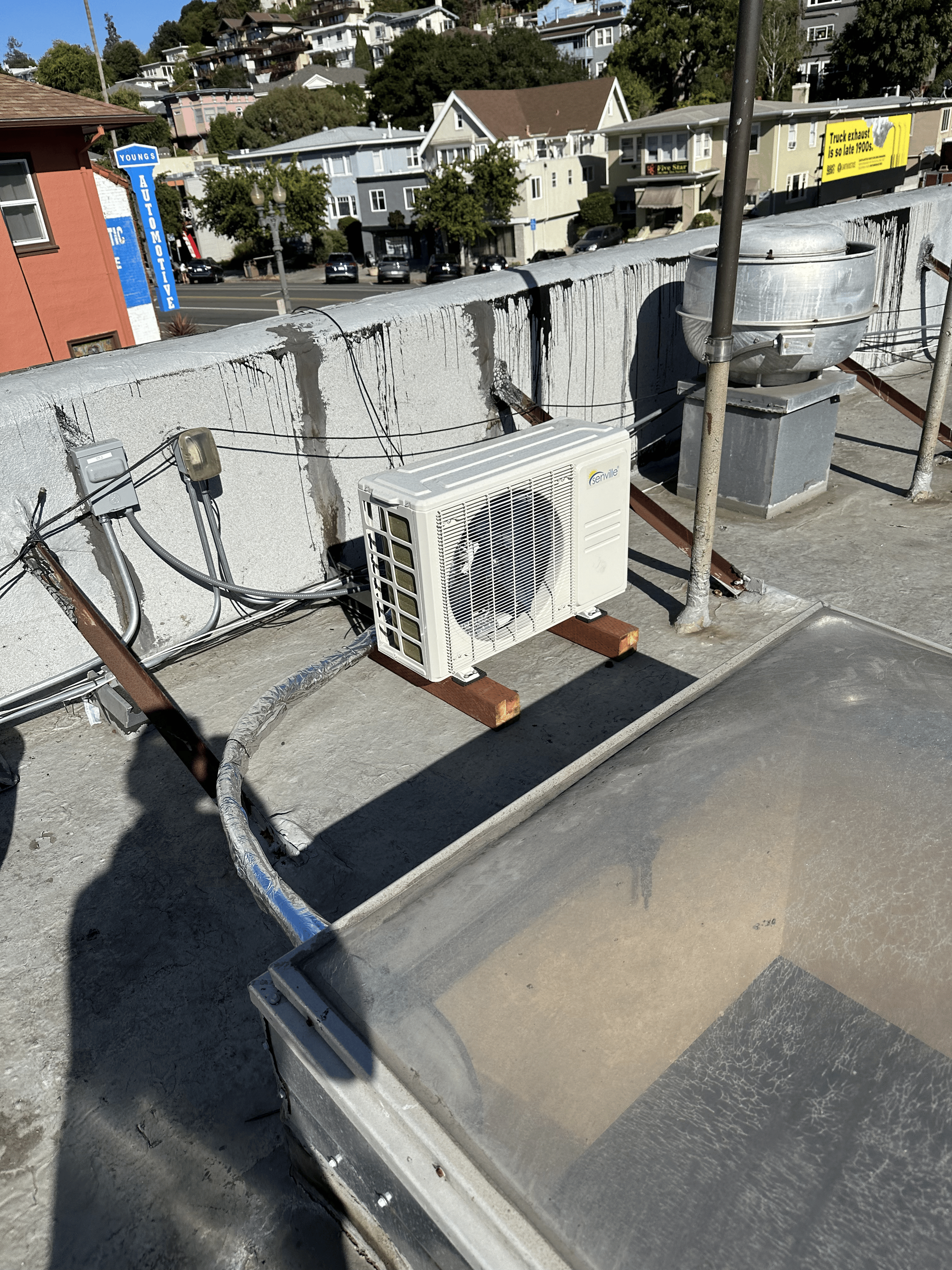 A white air conditioner is sitting on top of a roof.
