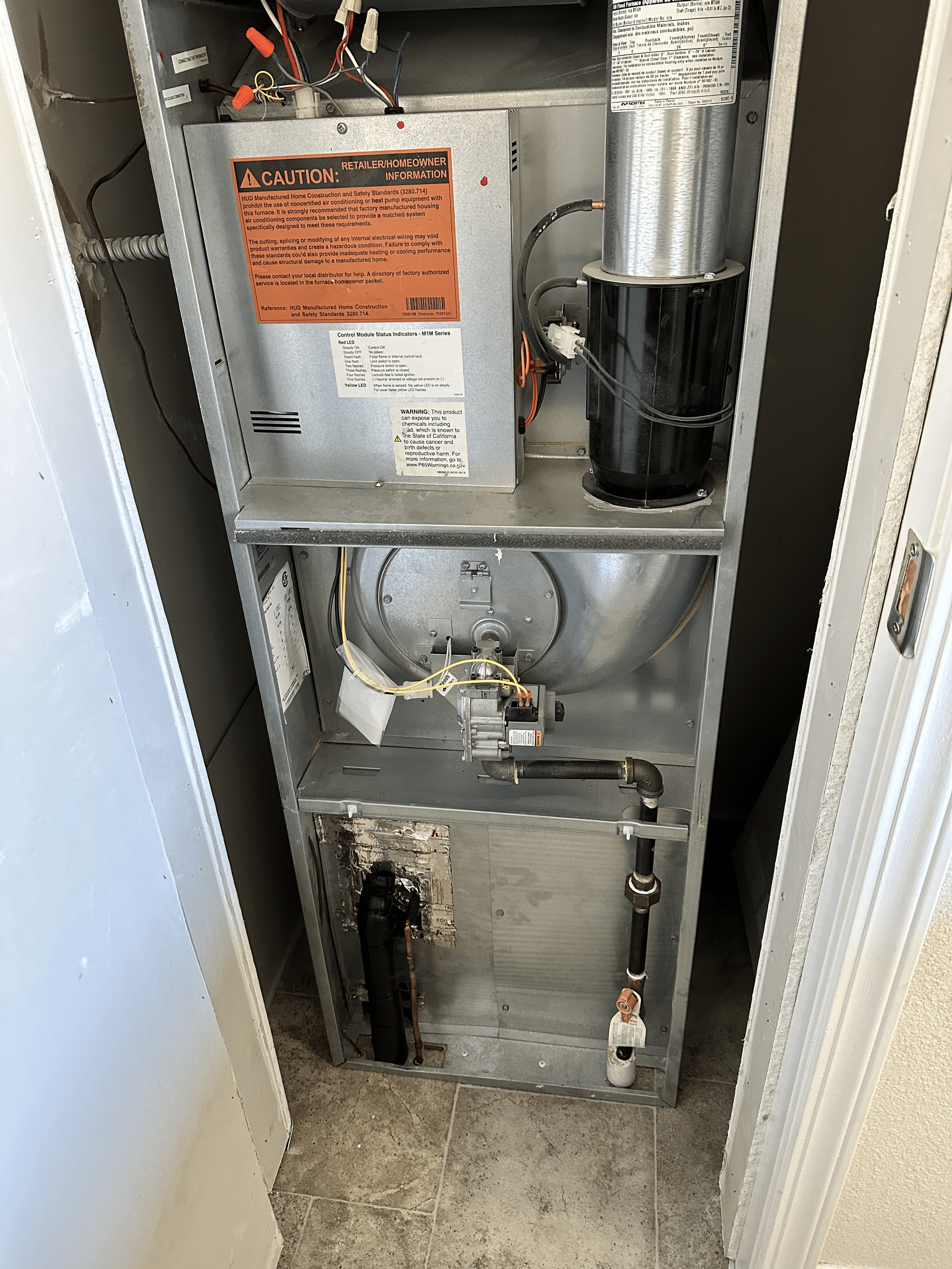 An air conditioner is sitting in a closet next to a door.