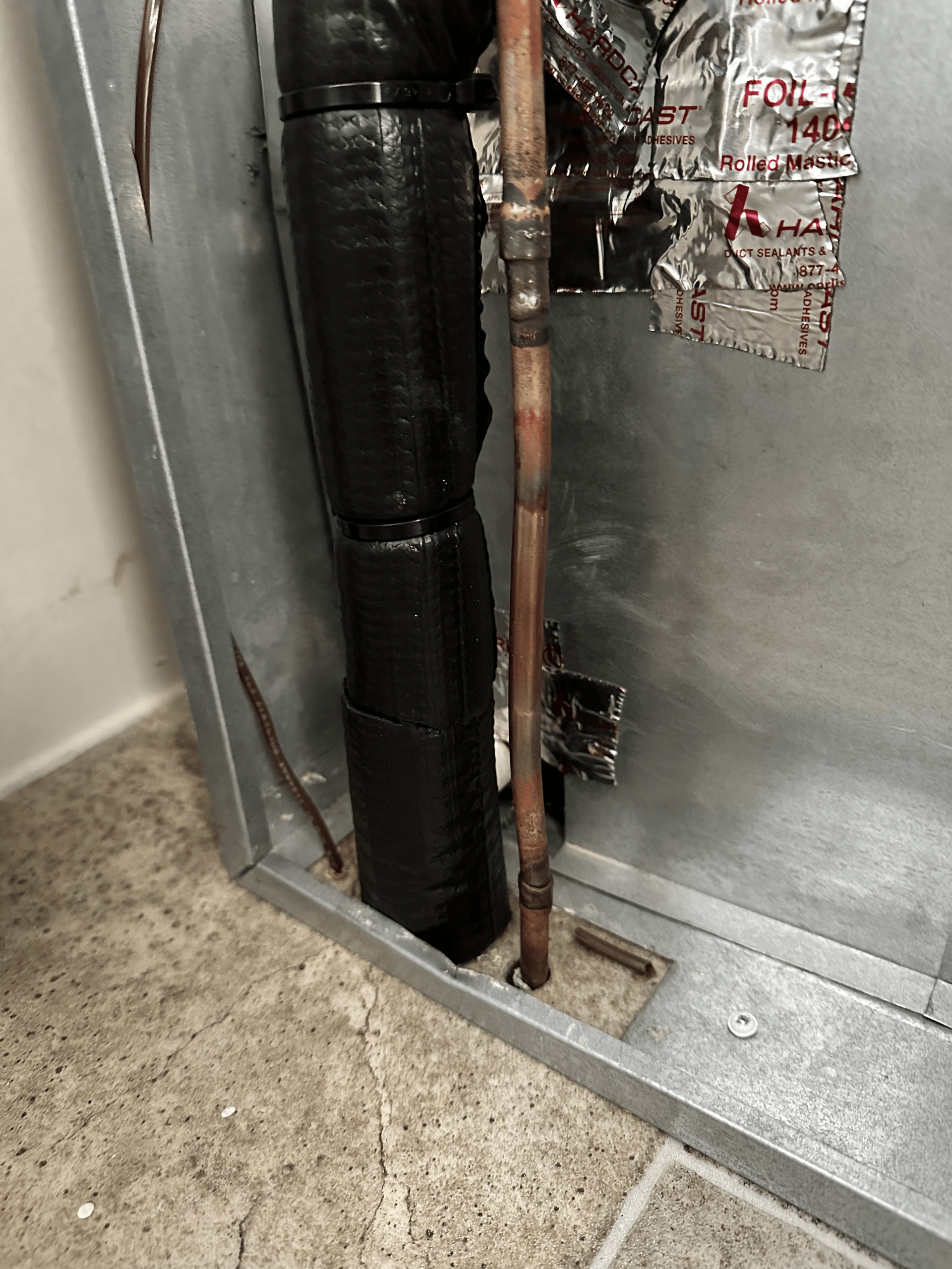 A close up of a copper pipe in a metal box.