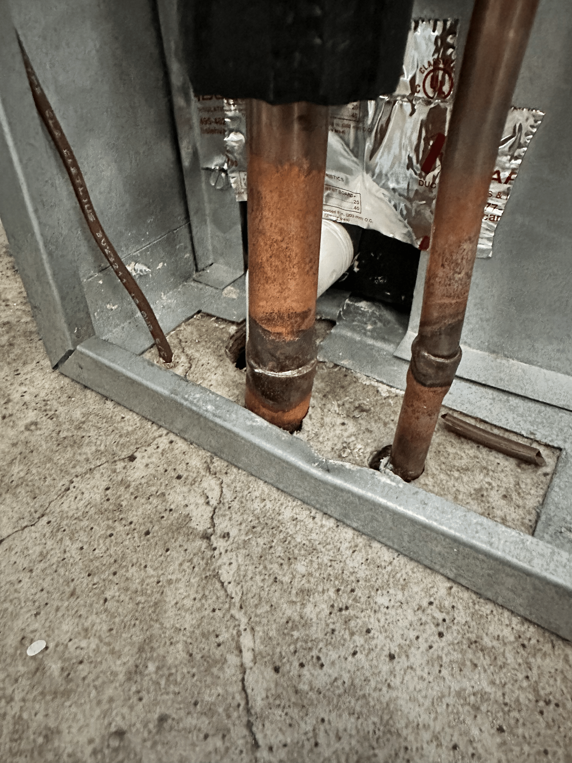 A close up of a copper pipe in a wall.