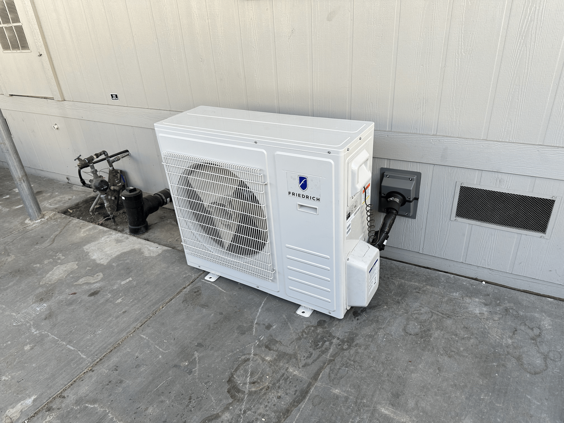A white air conditioner is sitting on the side of a building.