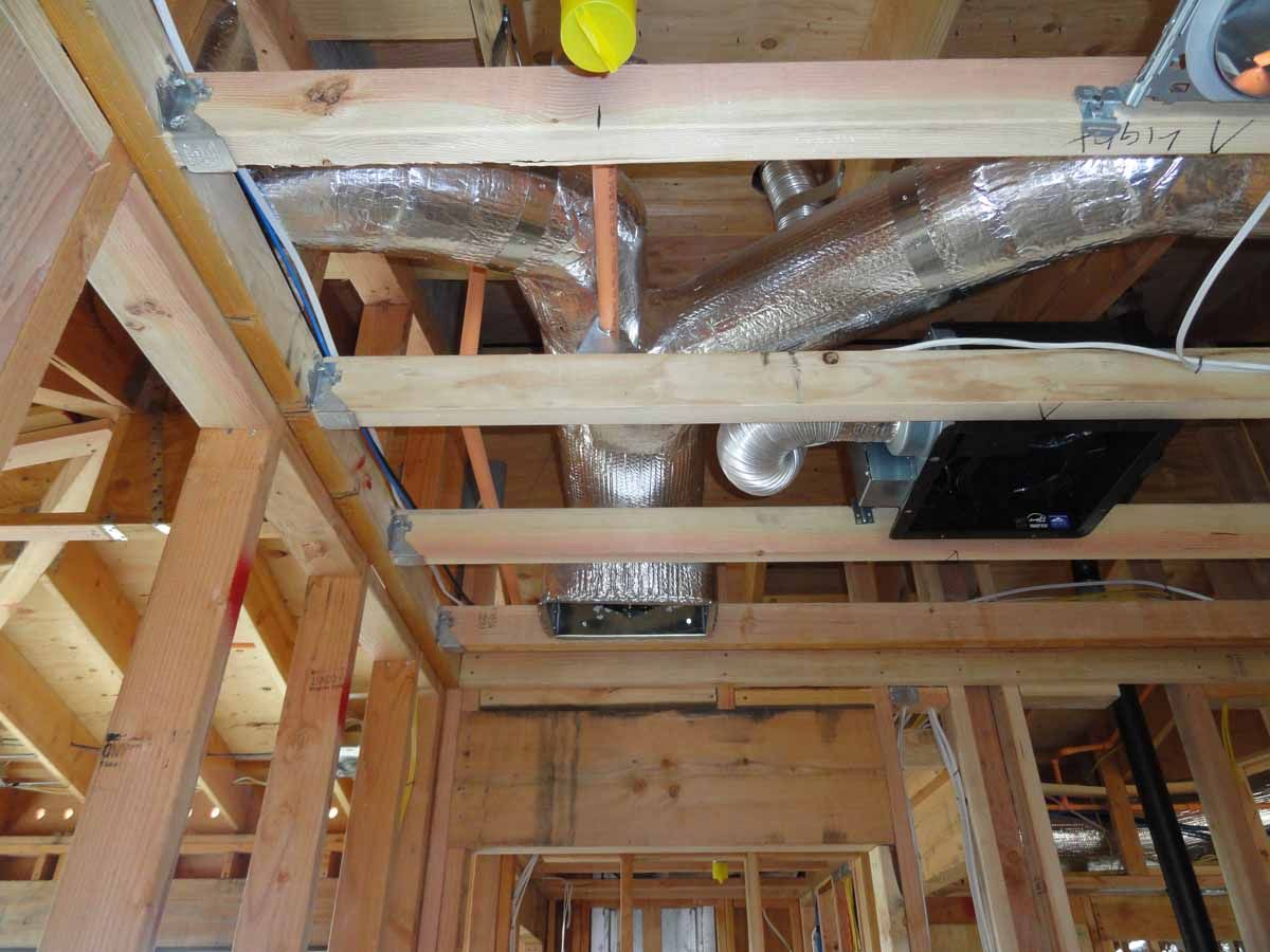 A house is being built with a lot of pipes coming out of the ceiling.