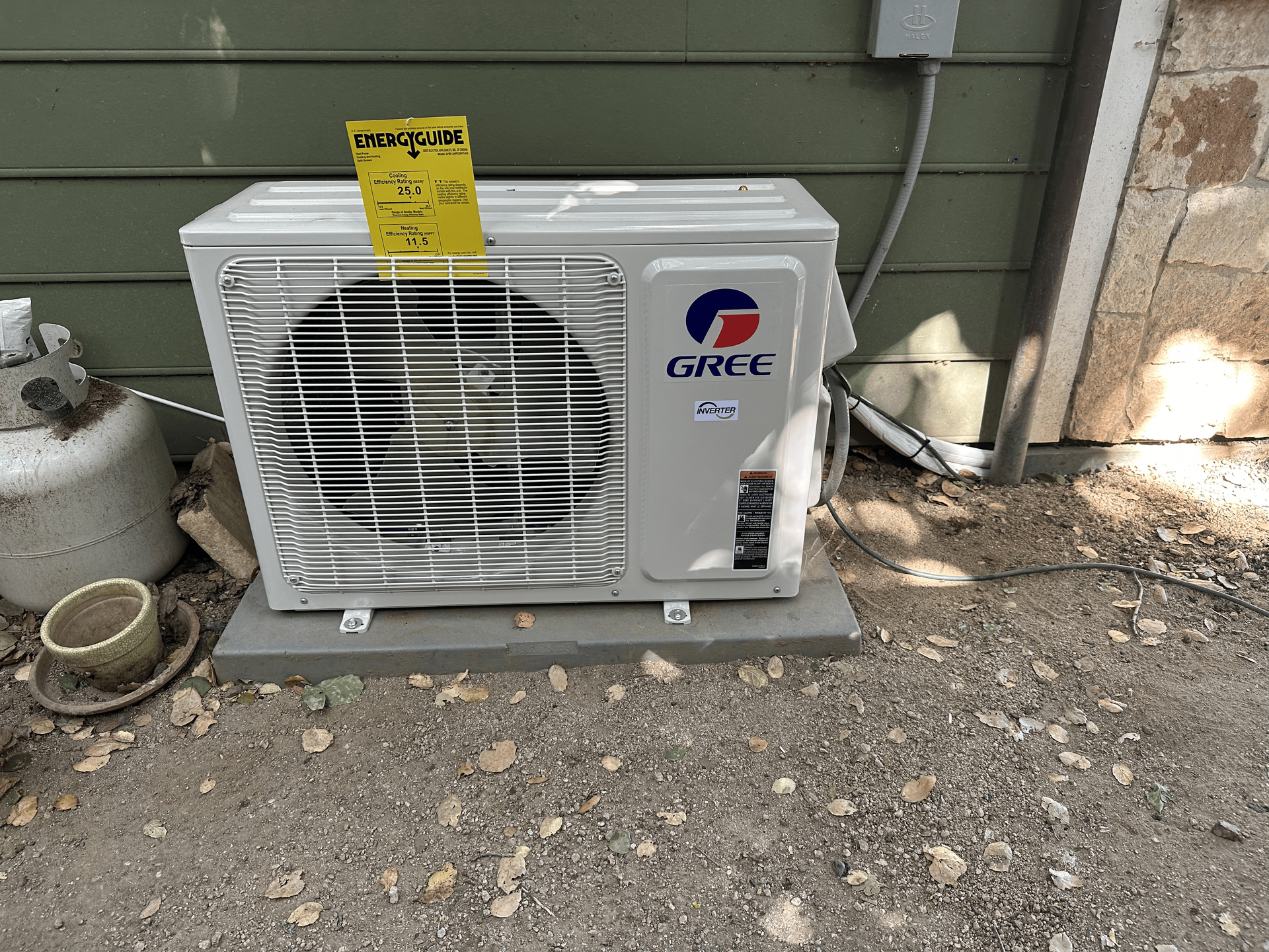 A gree air conditioner is sitting outside of a house.