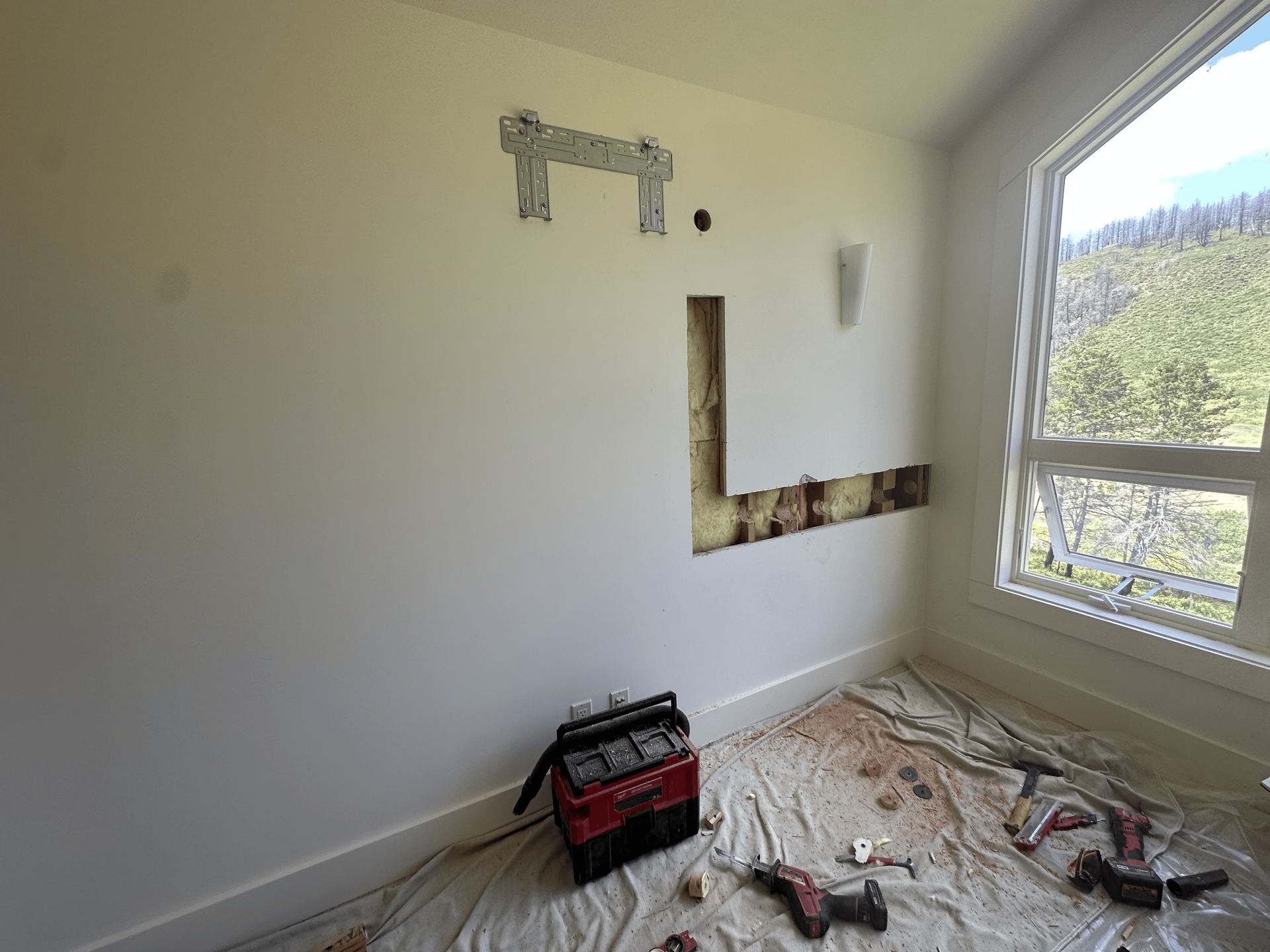 An empty room with a window and a toolbox on the floor.