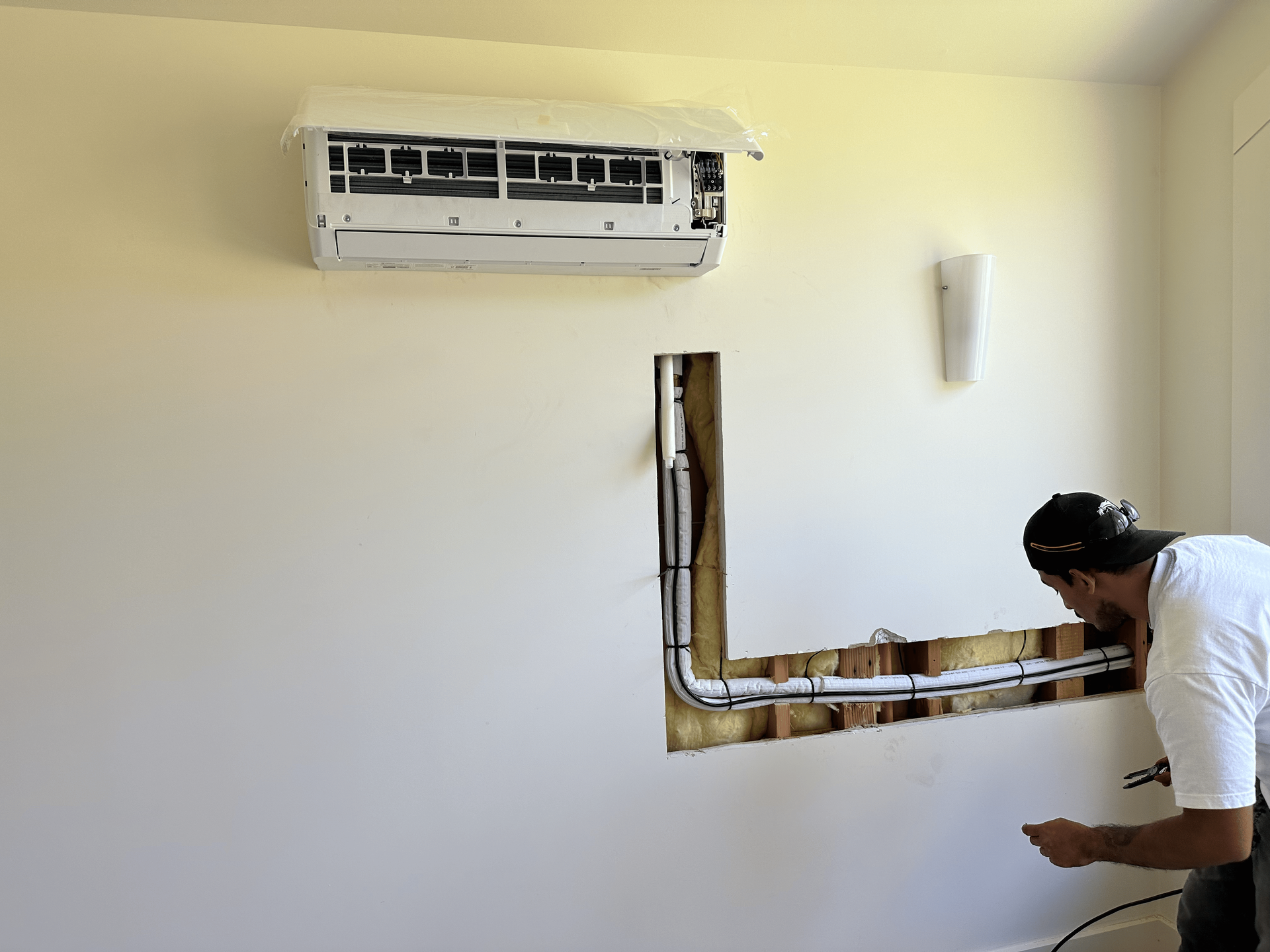 A man is working on an air conditioner in a room.