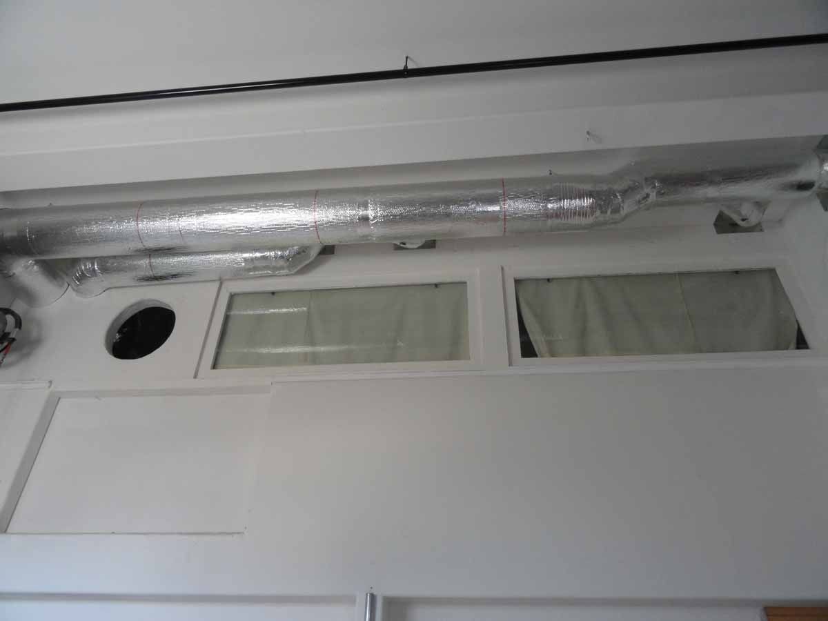 A white wall with a window and a pipe hanging from the ceiling.