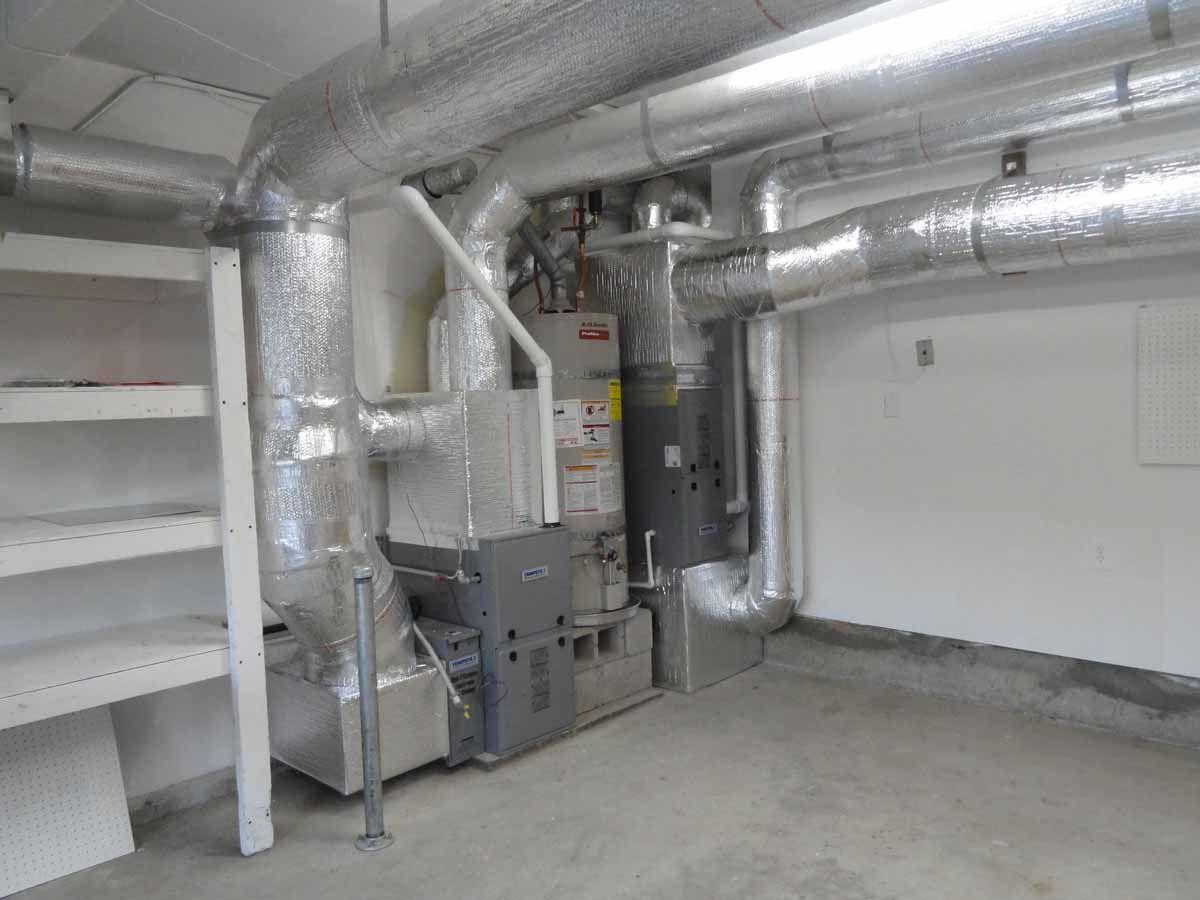 A room with a lot of pipes and a furnace in it.