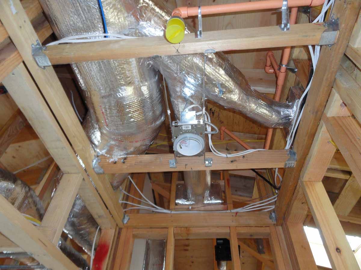 A ceiling with a lot of pipes and wires hanging from it