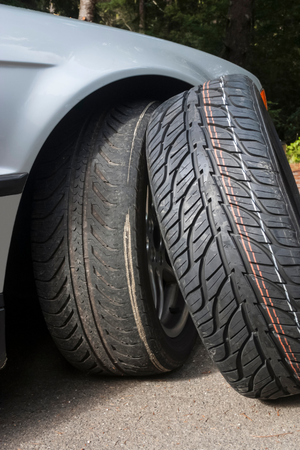 Two tires are stacked on top of each other on the side of a car.