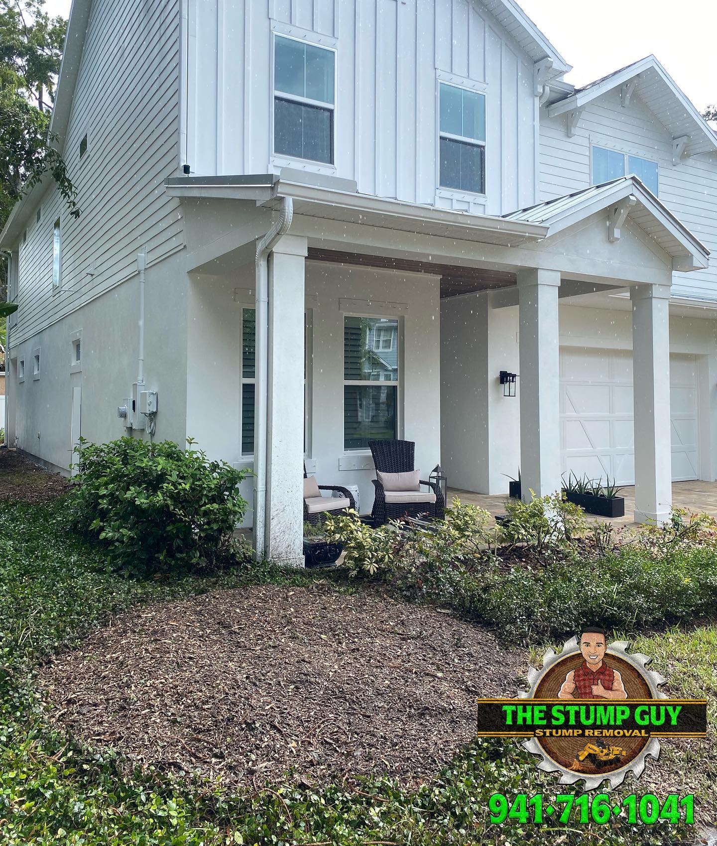 White two-story house with porch and landscaping. 