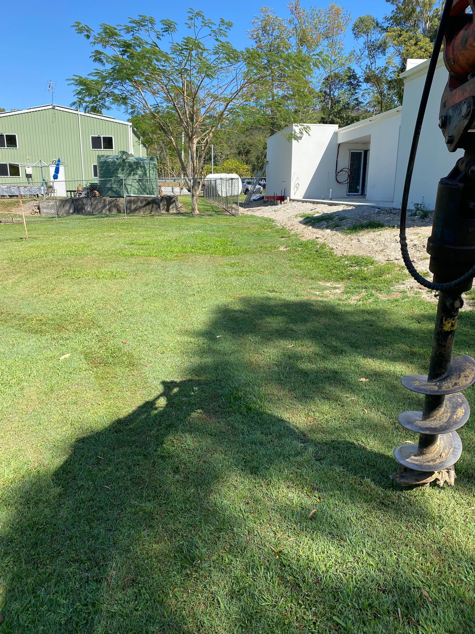A drill on green grass. White and green buildings in the background. Bright sunlight.