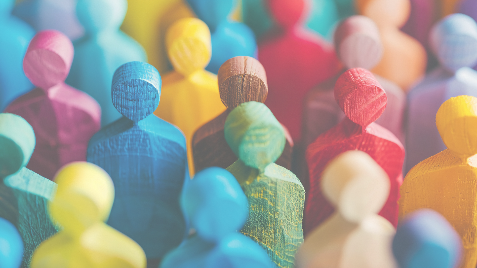 Figurines made out of wood in the shape of people, with all being different colors. 