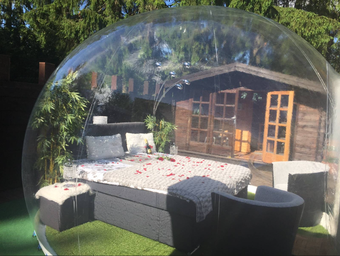 Ein Bubble-Hotel mit einem Bett und Stühlen darin.