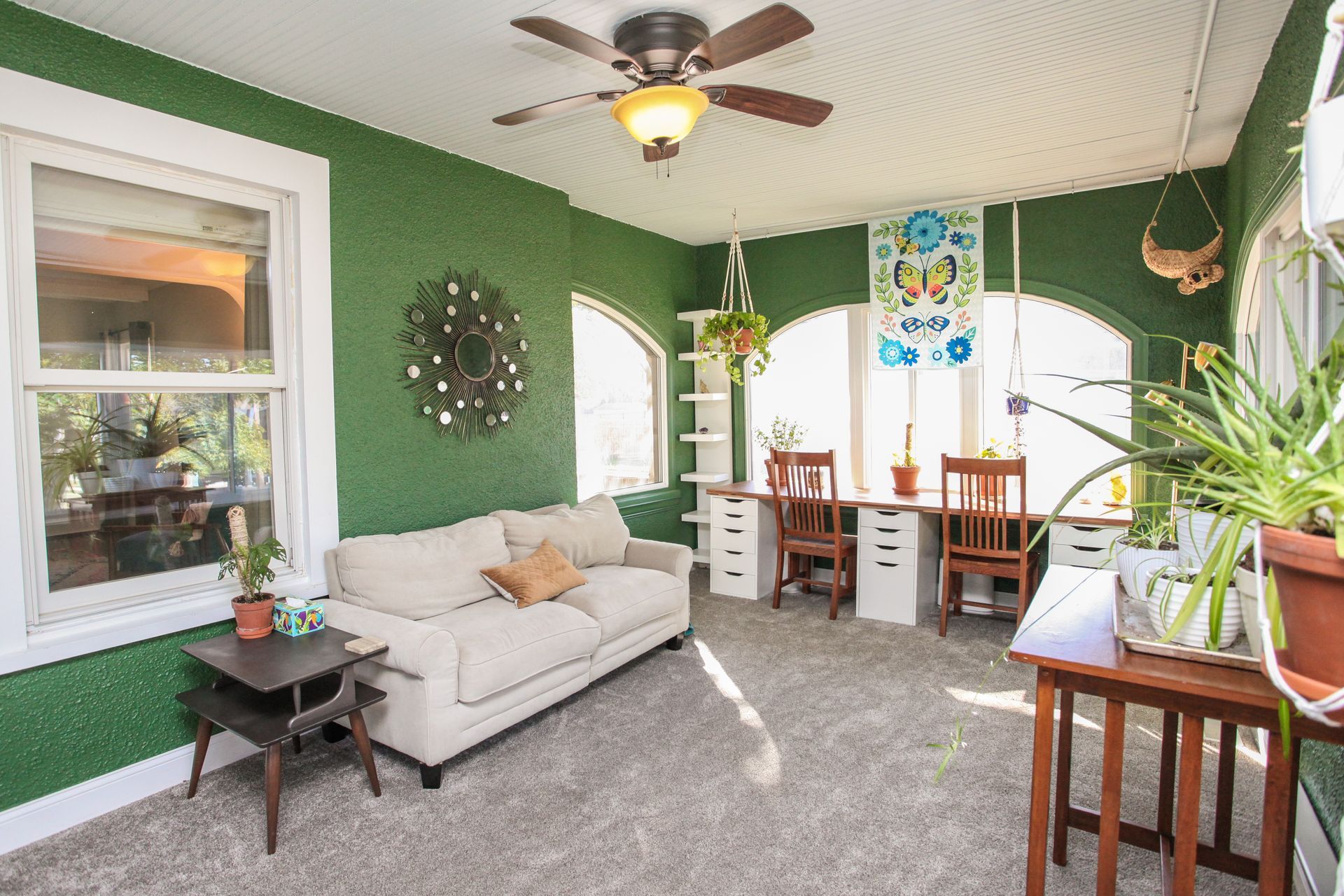 Sun porch painted dark green with couch and bright windows