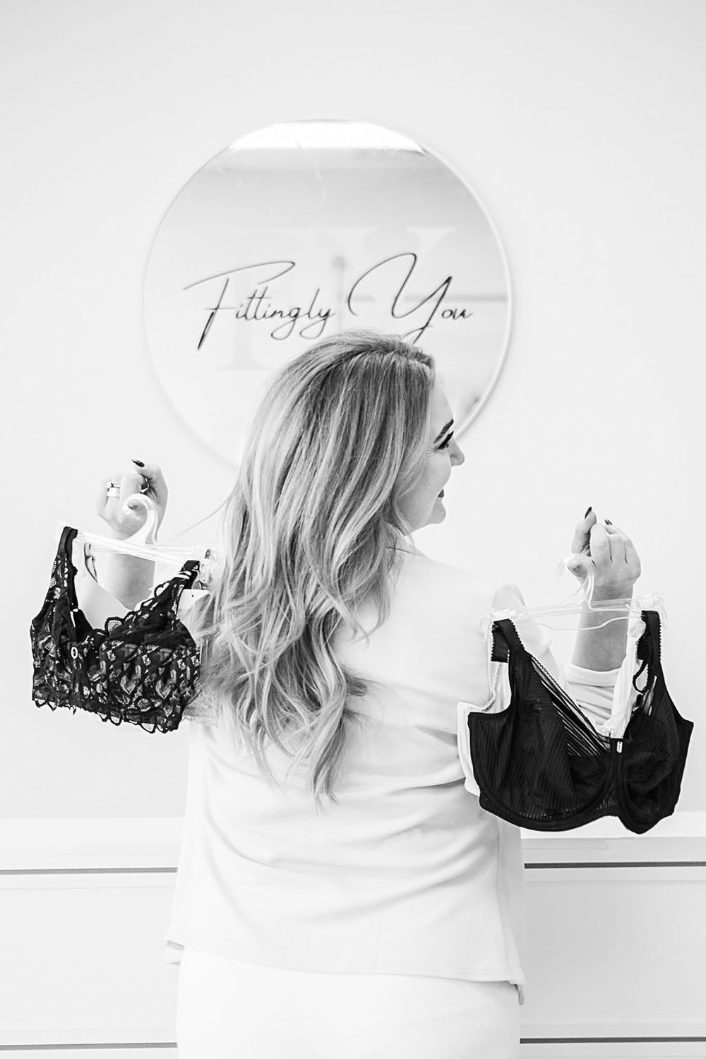 Bra store owner showcasing several bras over her shoulder
