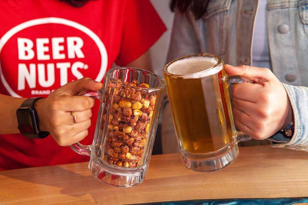 cheers with a cup of Beer Nuts and a Beer